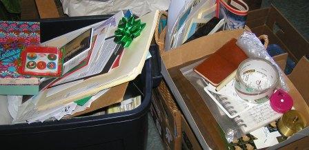 Boxes full of trinkets and clutter, including cards, magazines, packing tape and a Christmas bow.