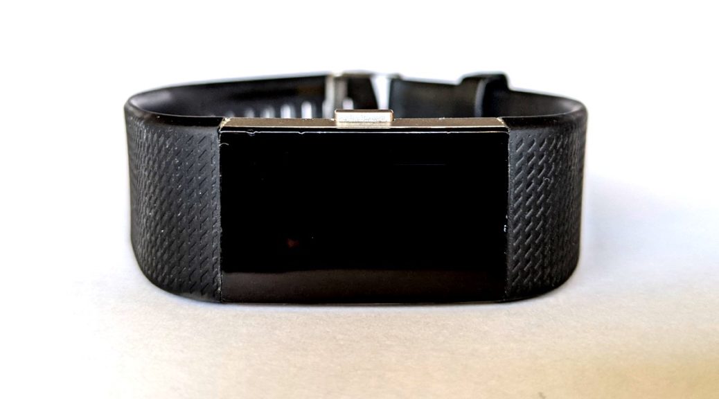 Fitbit Charge 2 fitness band with a blank face because it stopped working. Black band and small chips around the face because it's been used.